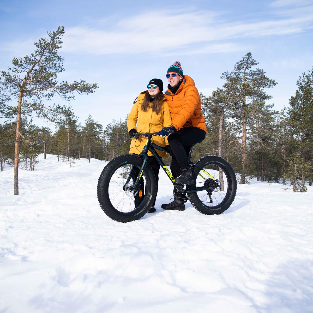 Nainen ja mies polkupyörän kanssa talvisessa luonnossa.